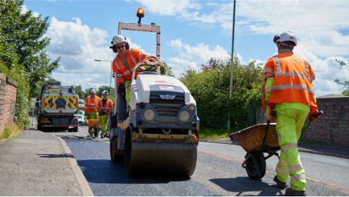 Multiple workers doing a mastic repair on a road